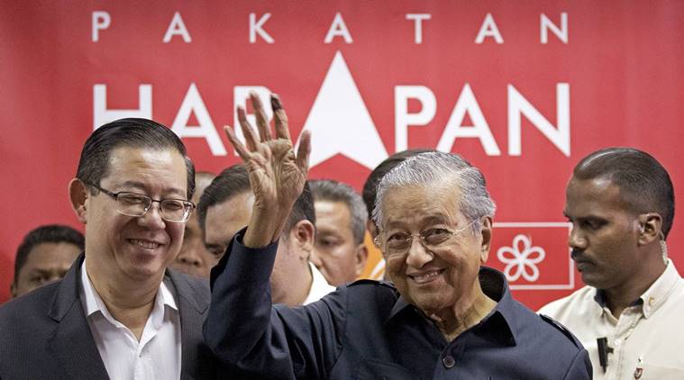 Malaysia's Prime Minister Mahathir Mohamad, center, waves next to newly appointed Finance Minister Lim Guan Eng, left, after a press conference to announce his cabinet members in Petaling Jaya, Malaysia, Saturday, May 12, 2018. Mahathir has appointed the ethnic Chinese as finance minister, the first ethnic minority to hold the powerful post in 44 years. (AP Photo/Andy Wong)